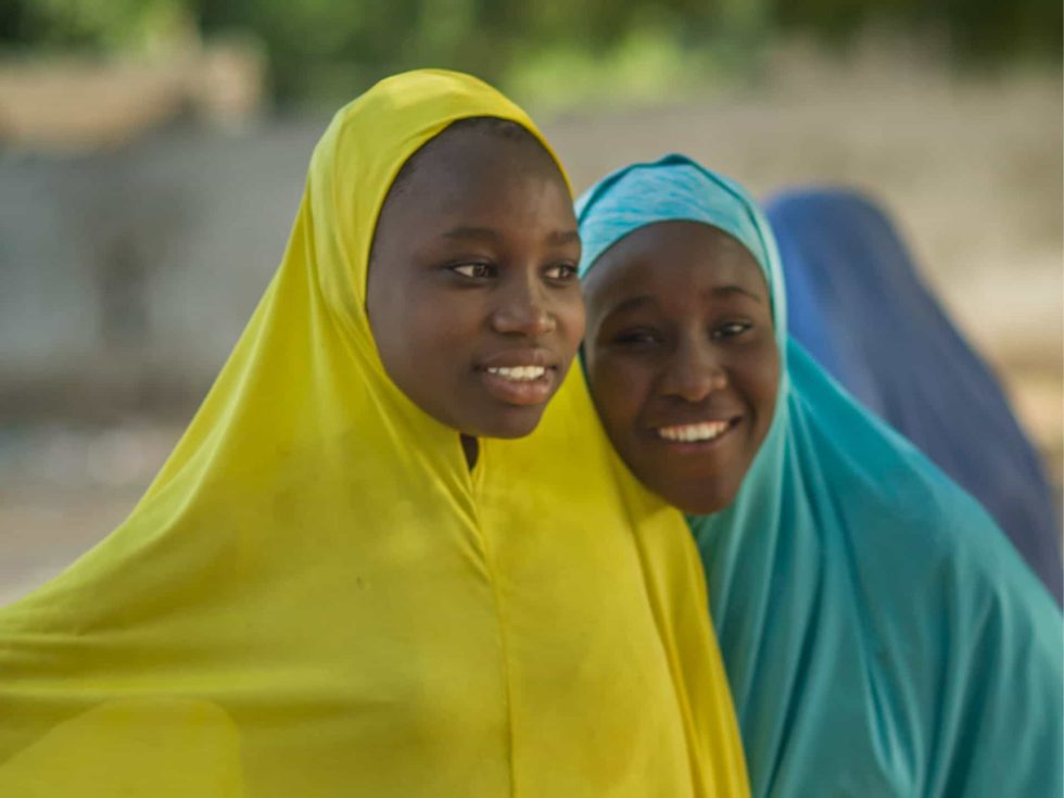 MAG - Freeing people from fear. Two young girls wearing brightly coloured covering smiling for the camera.