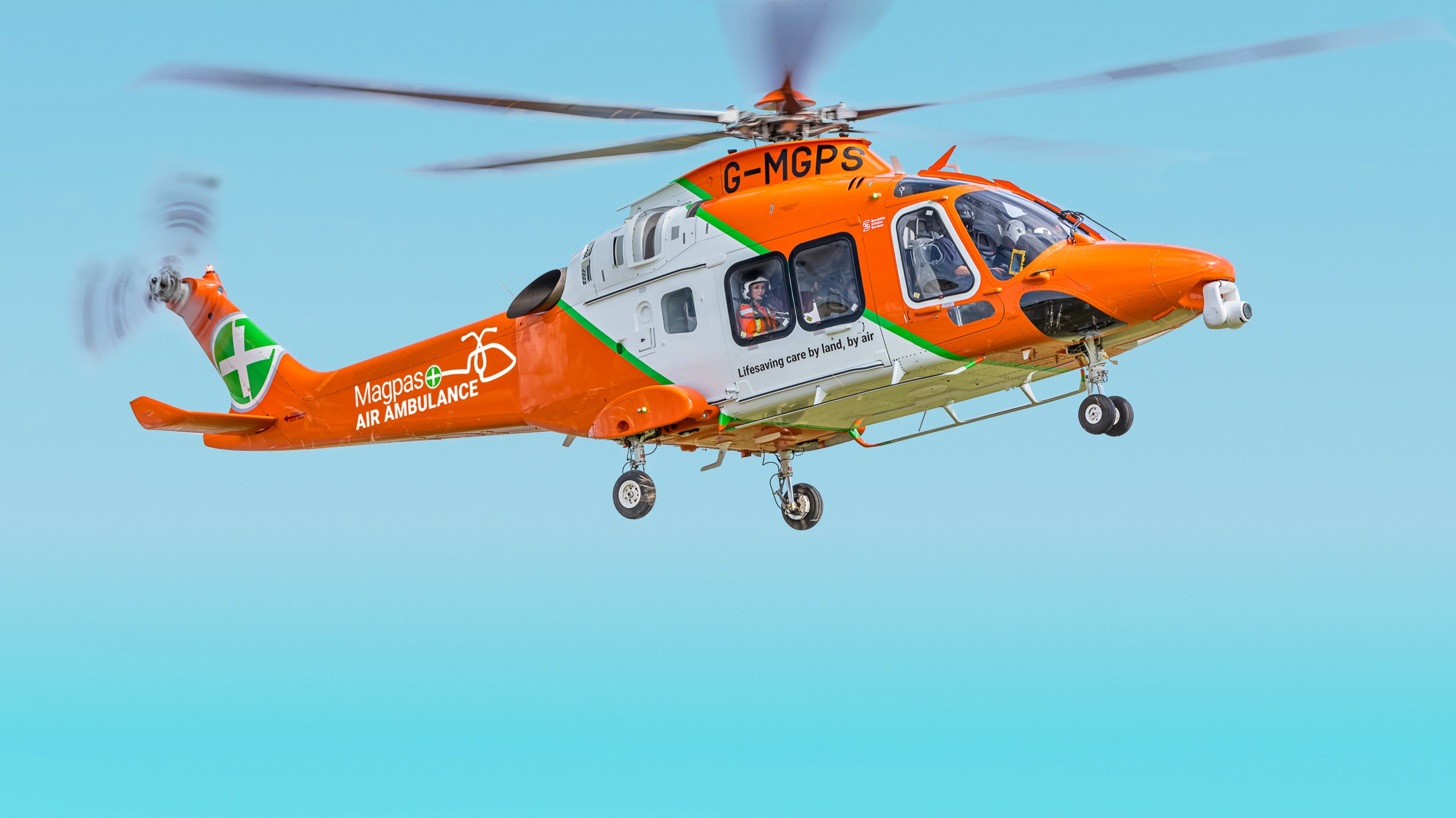 MAGPAS - Building a Brand to Fly Higher. A MAGPAS orange, white and green medical helicopter hovering in mid air.