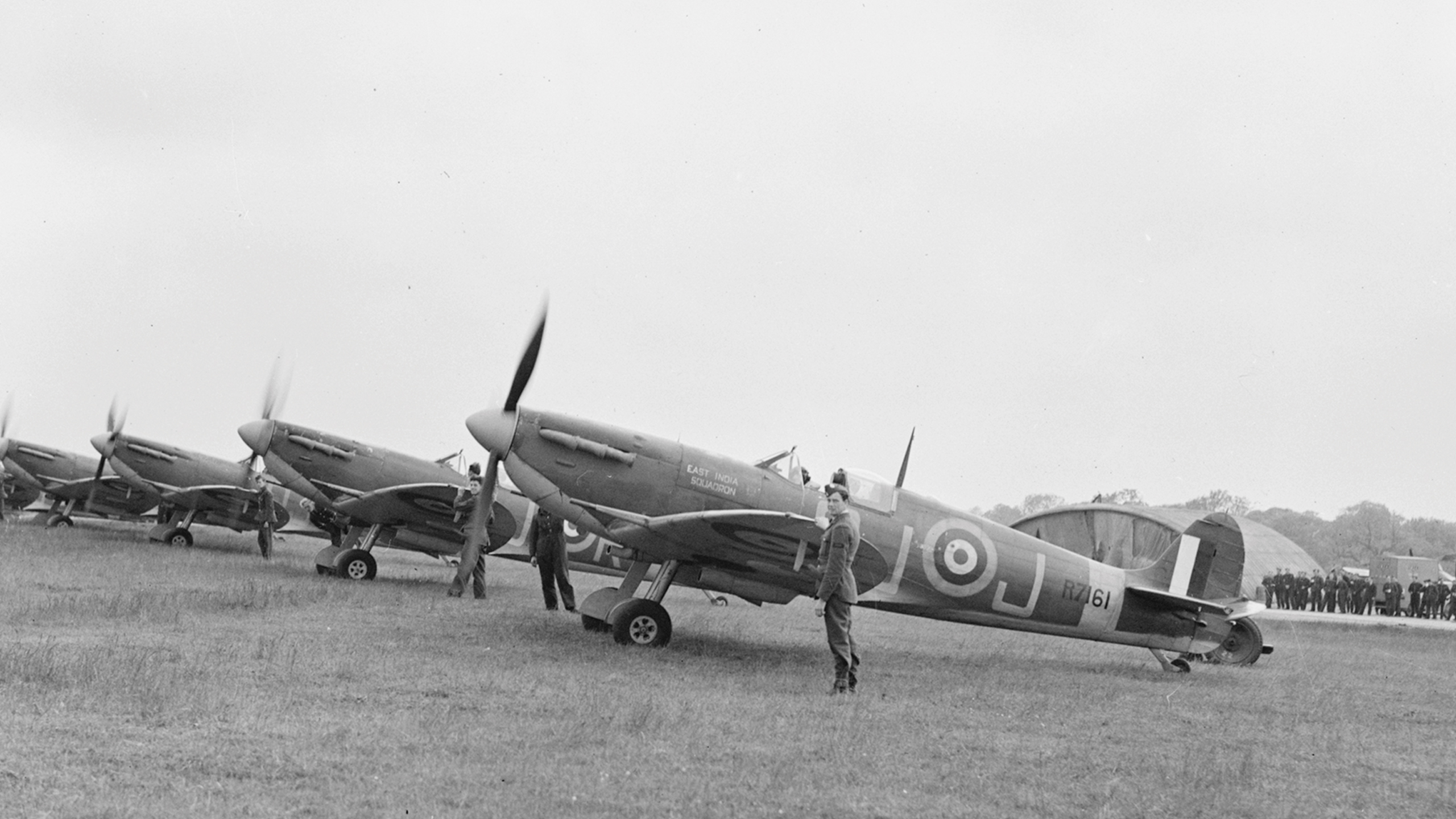 RAFA - Making a solemn pledge. Black and white photo of a group of veteran RAF pilots surroundoing a Spitfire plane.